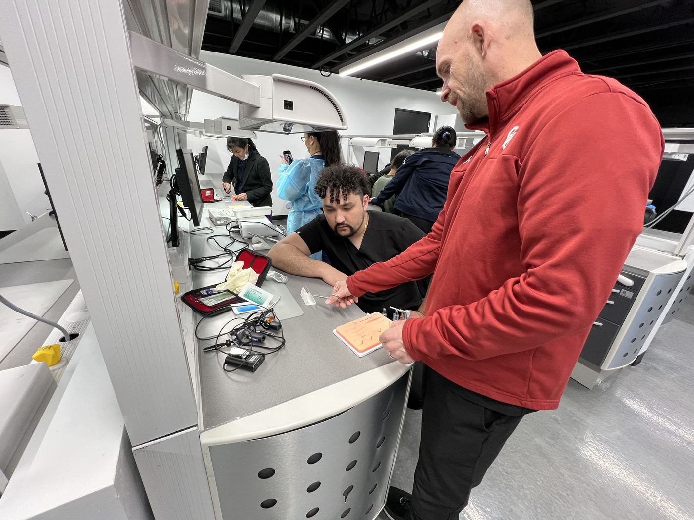 Instructor coaching a dentist through suturing technique in the Level 1 dental implant cadaver course